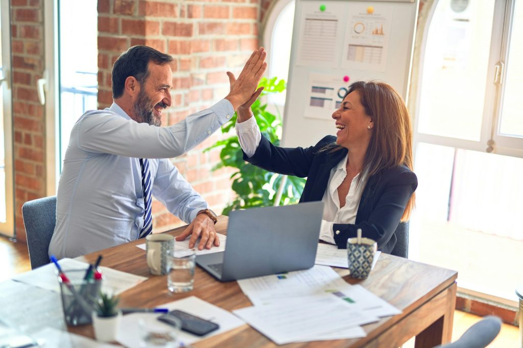 Agence marketing Aix-en-Provence : résultats clients Consultante et client de l’agence marketing BMO Conseil se tapant dans la main devant un ordinateur